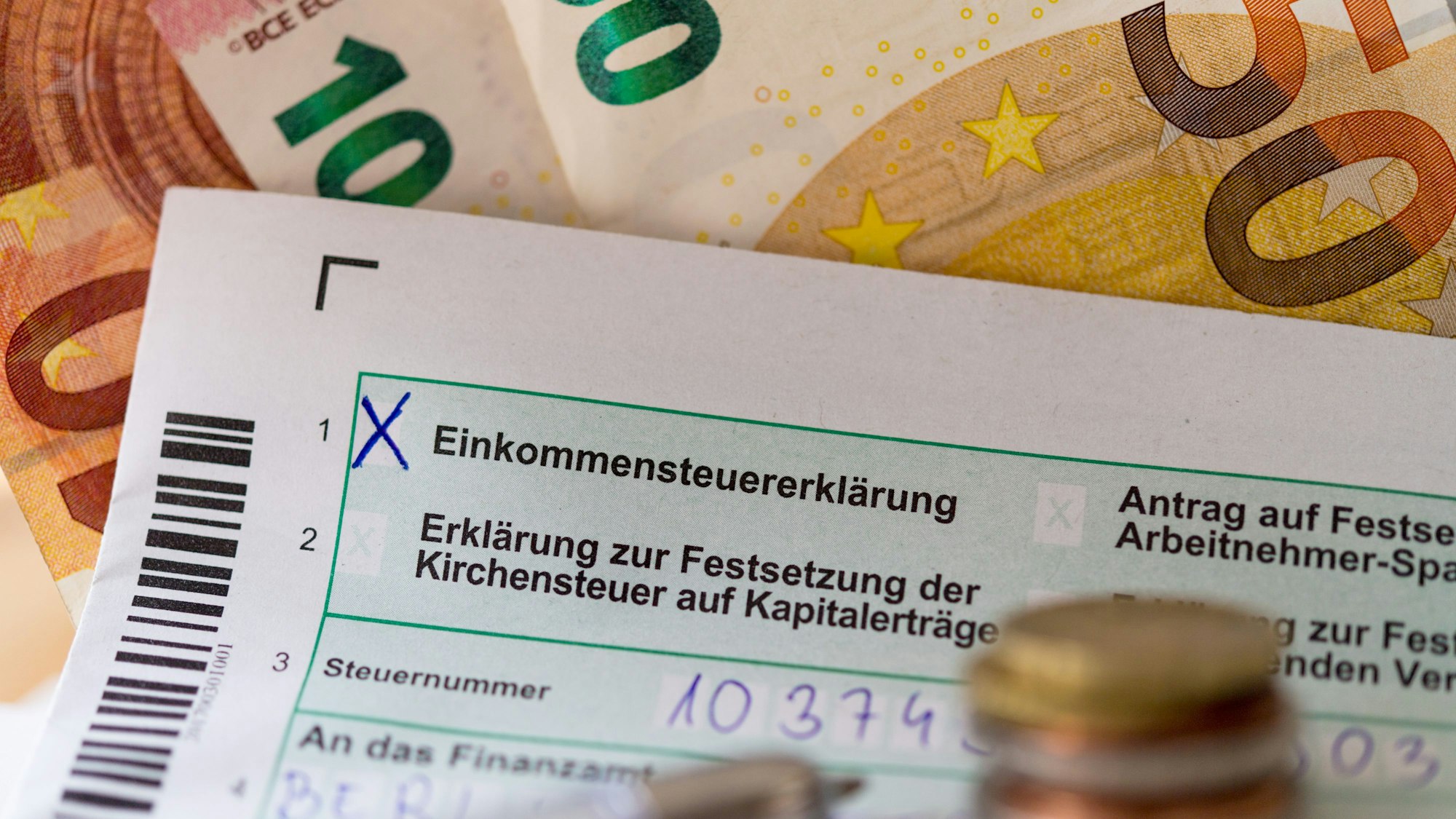 Eine Einkommensteuererklärung und Euro-Münzen liegen auf einem Tisch