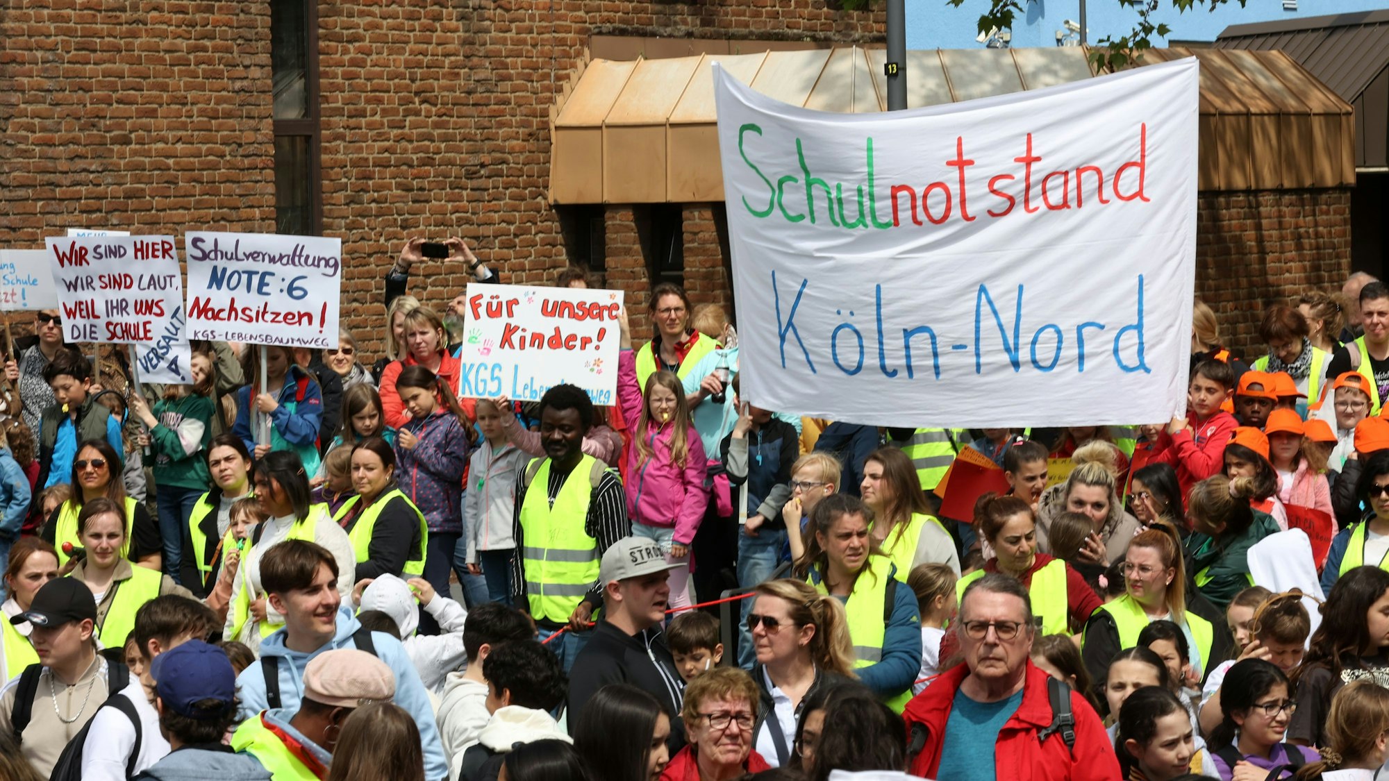 Eine Menge von Eltern und Schülern - teils in gelben Warnwesten