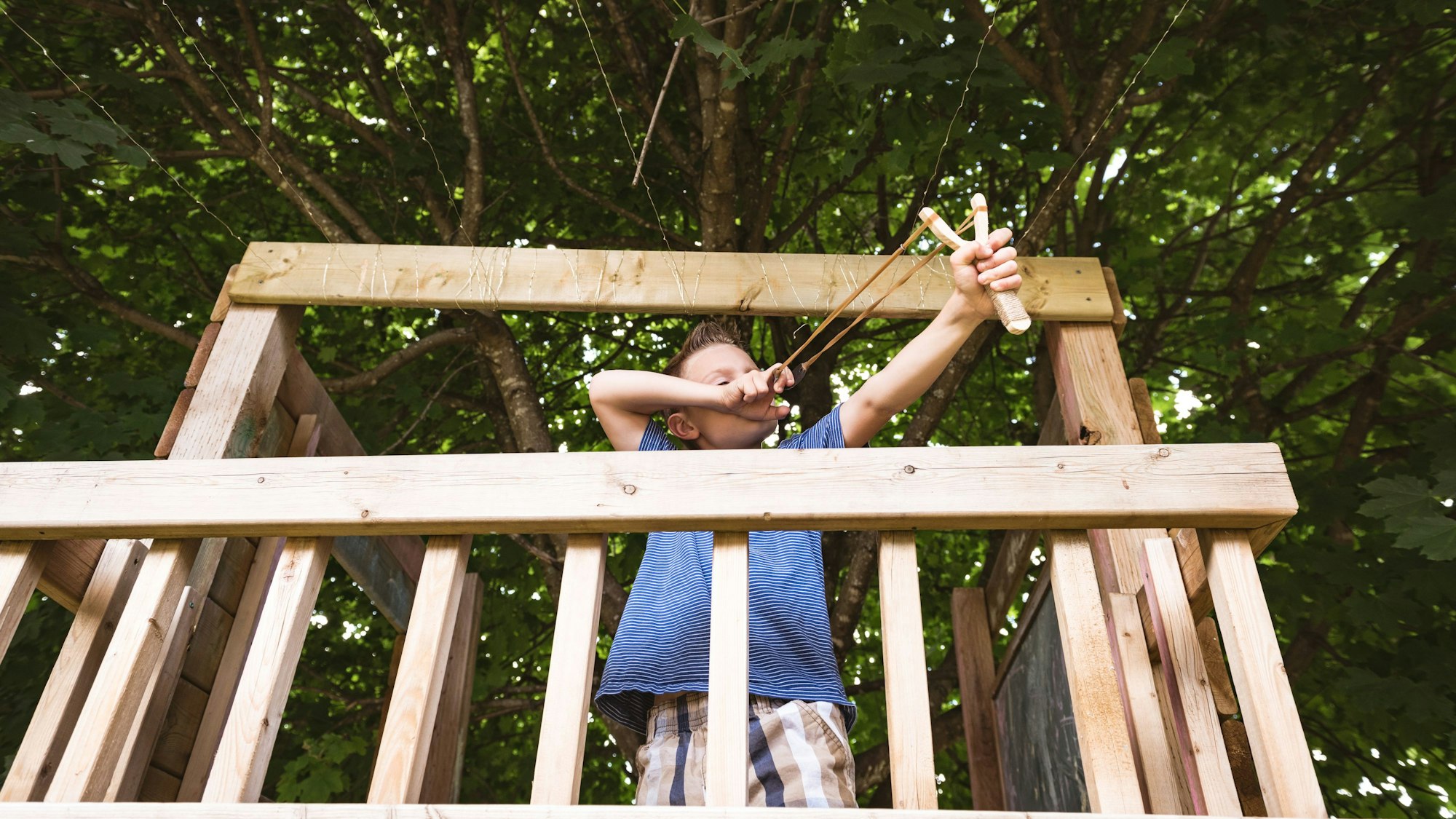 Ein Junge spielt auf einem Baumhaus mit einer Steinschleuder (Symbolbild). In den USA hat ein 13-Jähriger ein vergleichbares Wurfgeschoss benutzt, um einen mutmaßlichen Entführer in die Flucht zu schlagen.