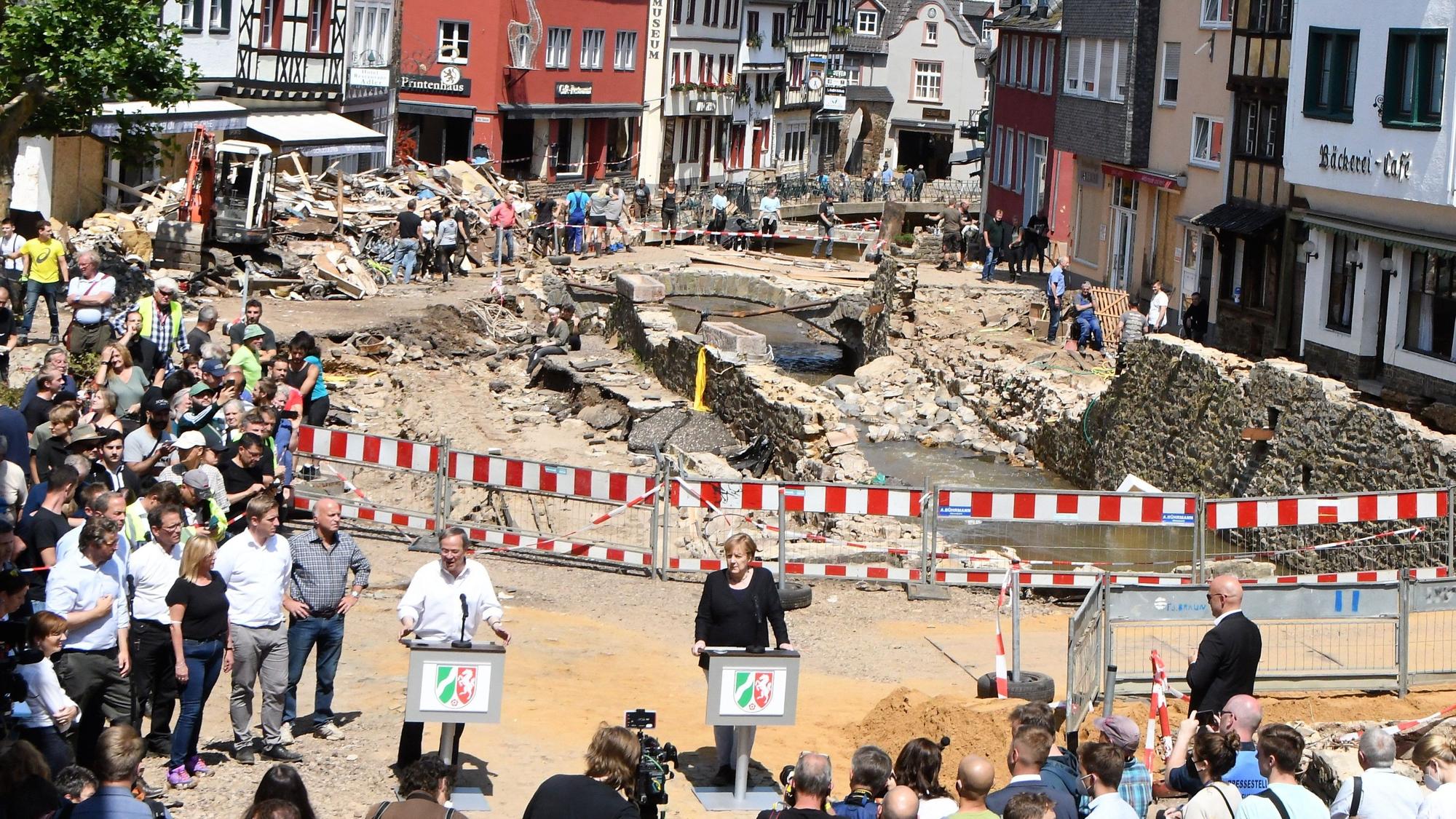 Das Bild aus den Tagen nach der Flutkatastrophe in Bad Münstereifel zeigt die damalige Bundeskanzlerin Angela Merkel und den damaligen NRW-Ministerpräsidenten Armin Laschet an Rednerpulten.