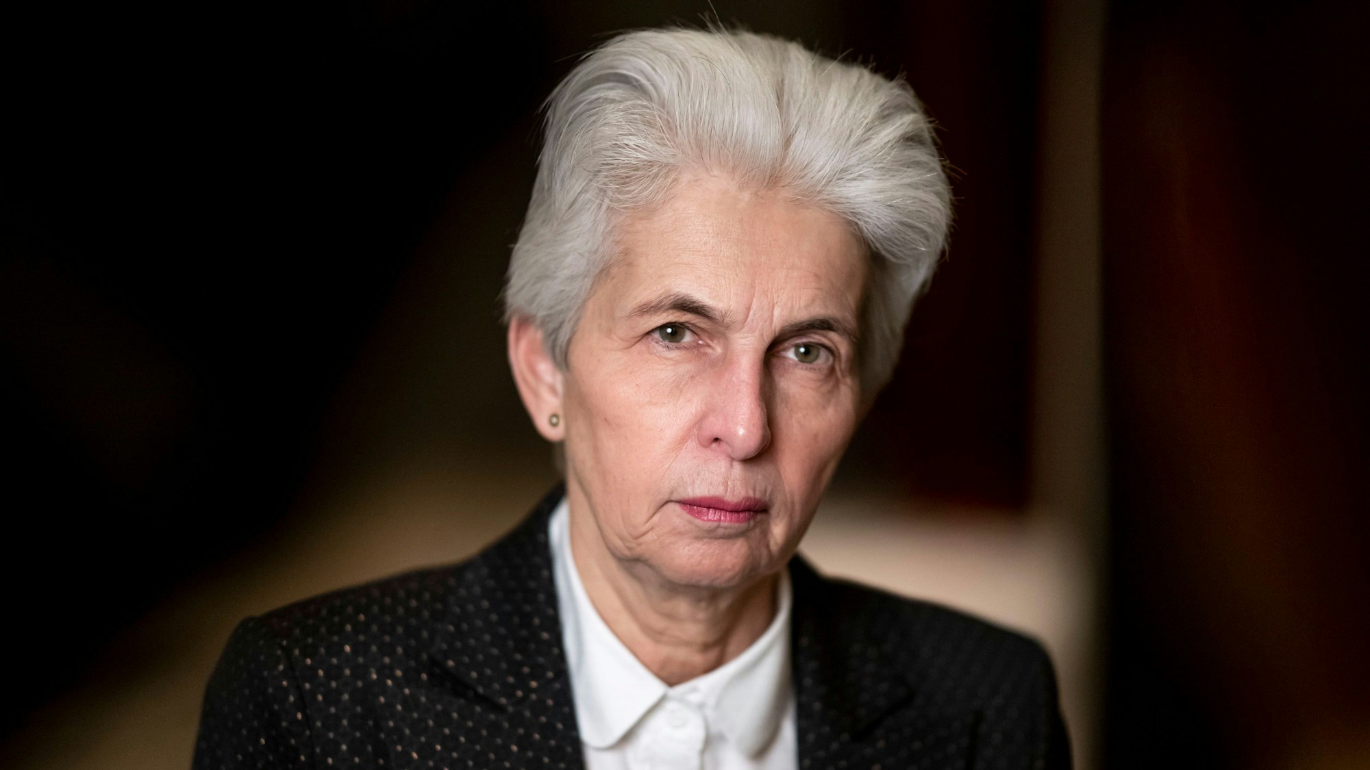 Marie-Agnes Strack-Zimmermann im Profil: Sie guckt in die Kamera, trägt ihre Haare weiß und kurz und hat ein schwarzes Jackett an, an der eine Ukraine-Brosche befestigt ist.