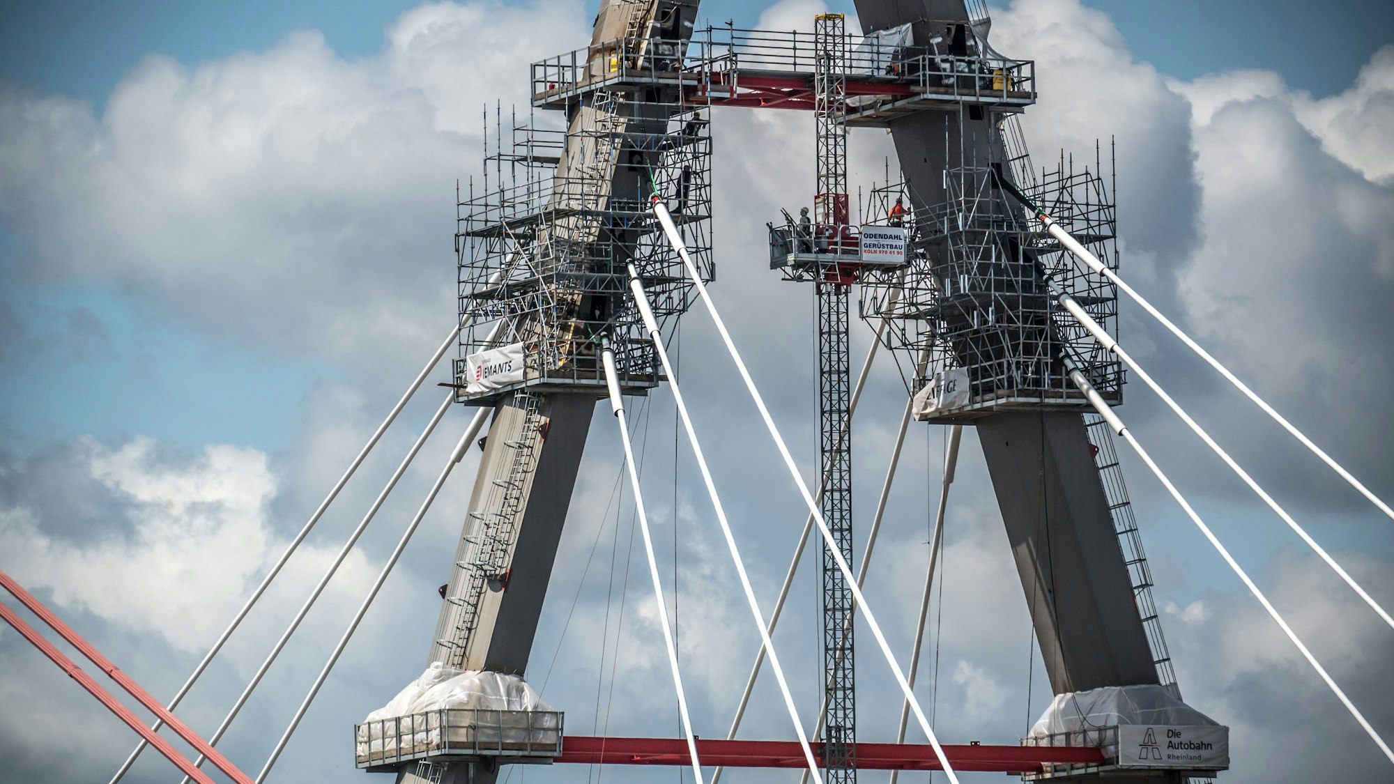 Der Pylon wird eingerüstet, die Tragseile werden nach und nach eingebaut.