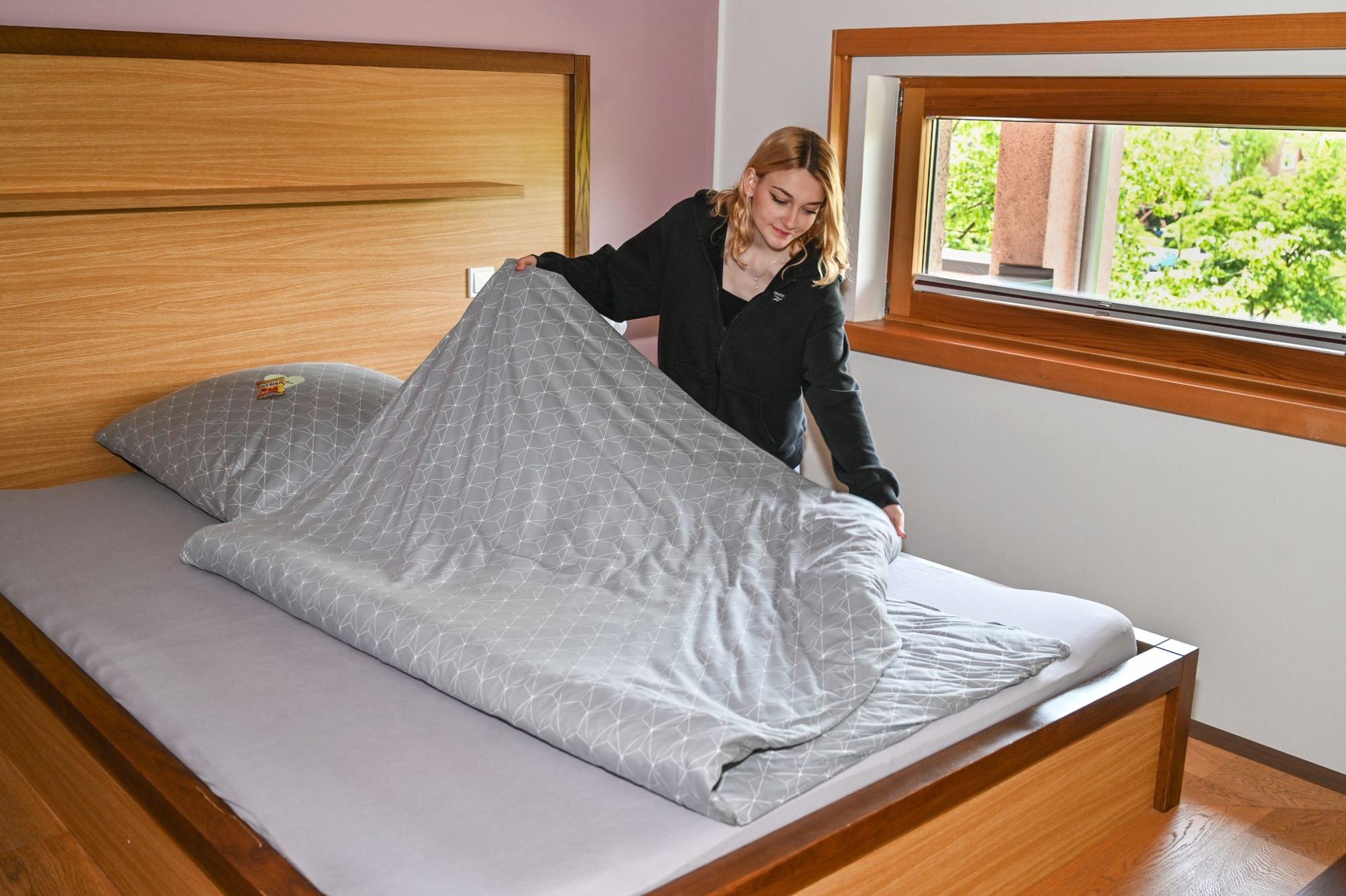 Eine junge Frau, die ein Bett macht, ist zu sehen.