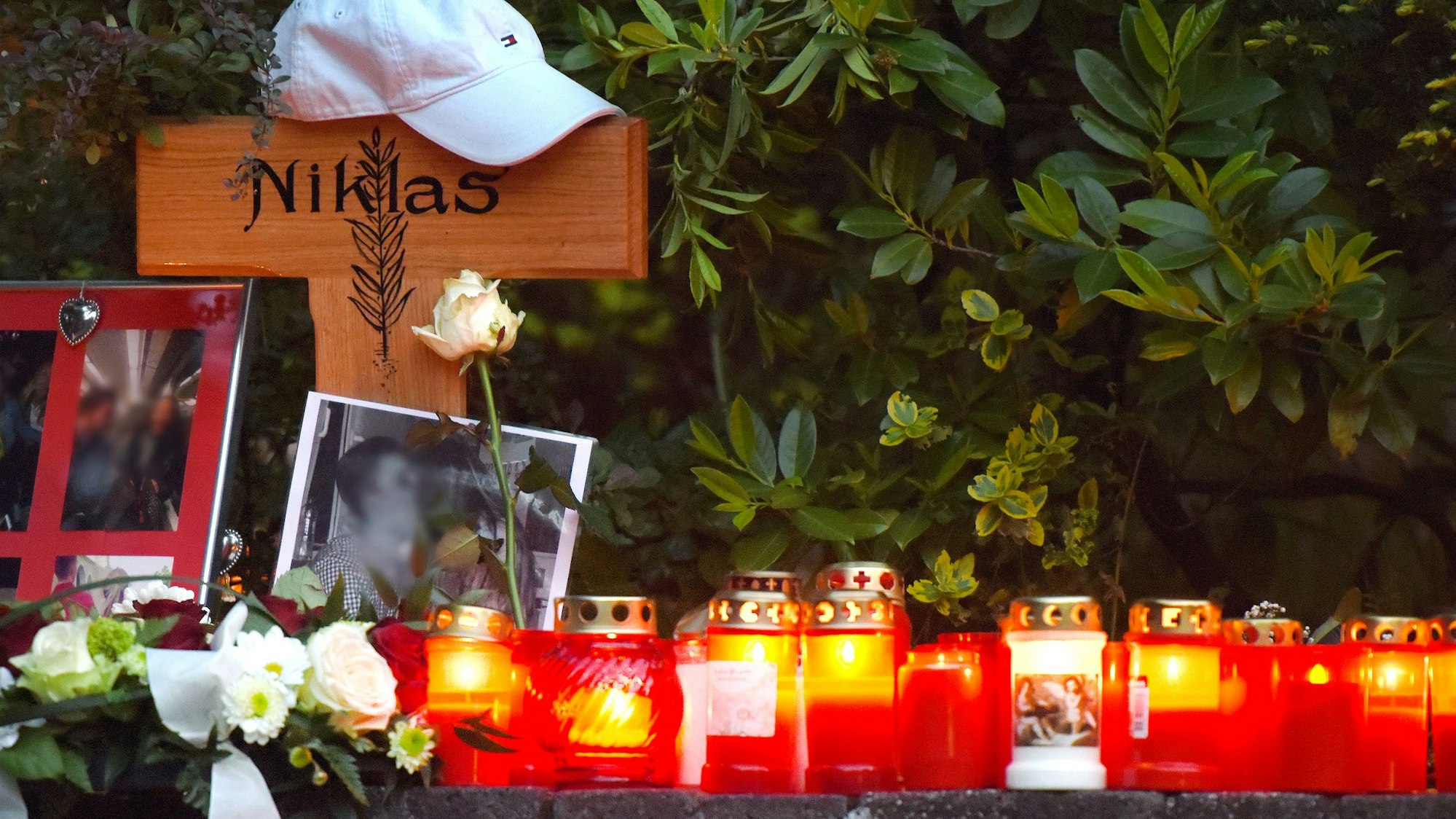 Blumen und Kerzen stehen vor und neben dem Kreuz an der Stelle, an der Niklas P. von Schlägern attackiert wurde.