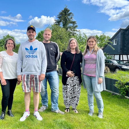 Fünf Eltern stehen in einem Garten