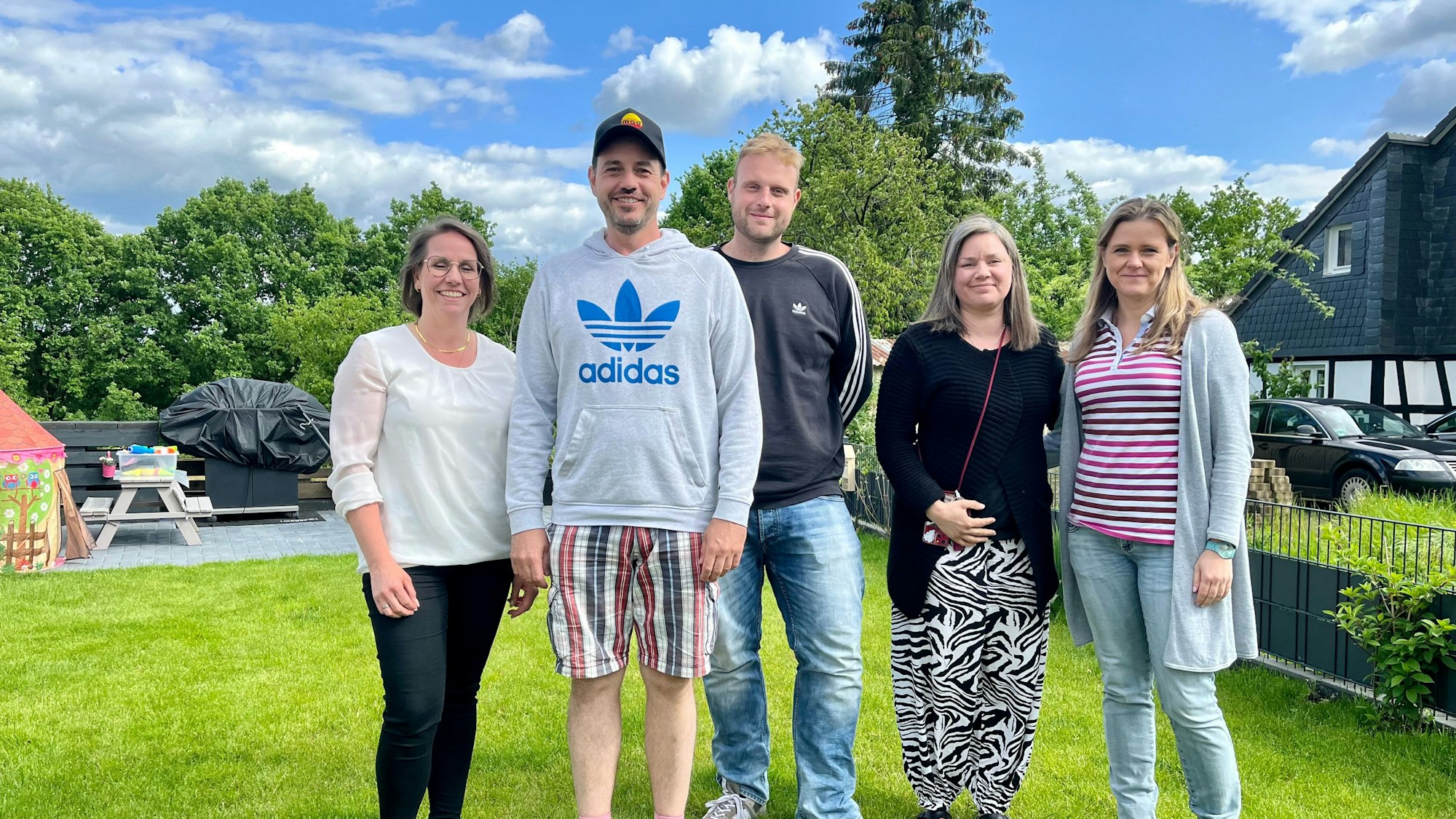Fünf Eltern stehen in einem Garten
