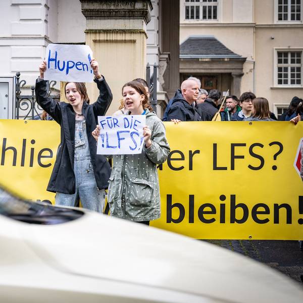 Mädchen halten Schilder in die Luft, auf denen „Hupen für die LFS“ steht.