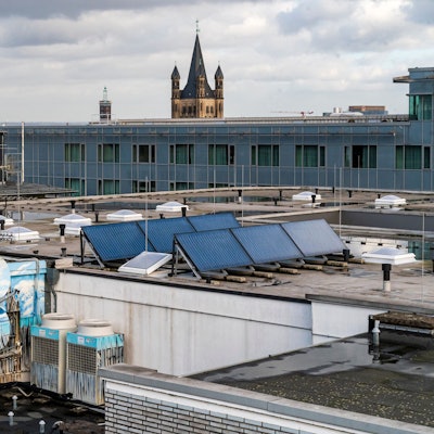 Solarzellen auf Gebäuden in der Kölner Innenstadt.
Hier: Ein Hotel- und Geschäftshaus an der Hohe Straße, Ecke Pipinstraße.
Im Hintergrund ist Groß St. Martin, und unten links, ein Graffiti was den Kölner Dom zeigt zu sehen.