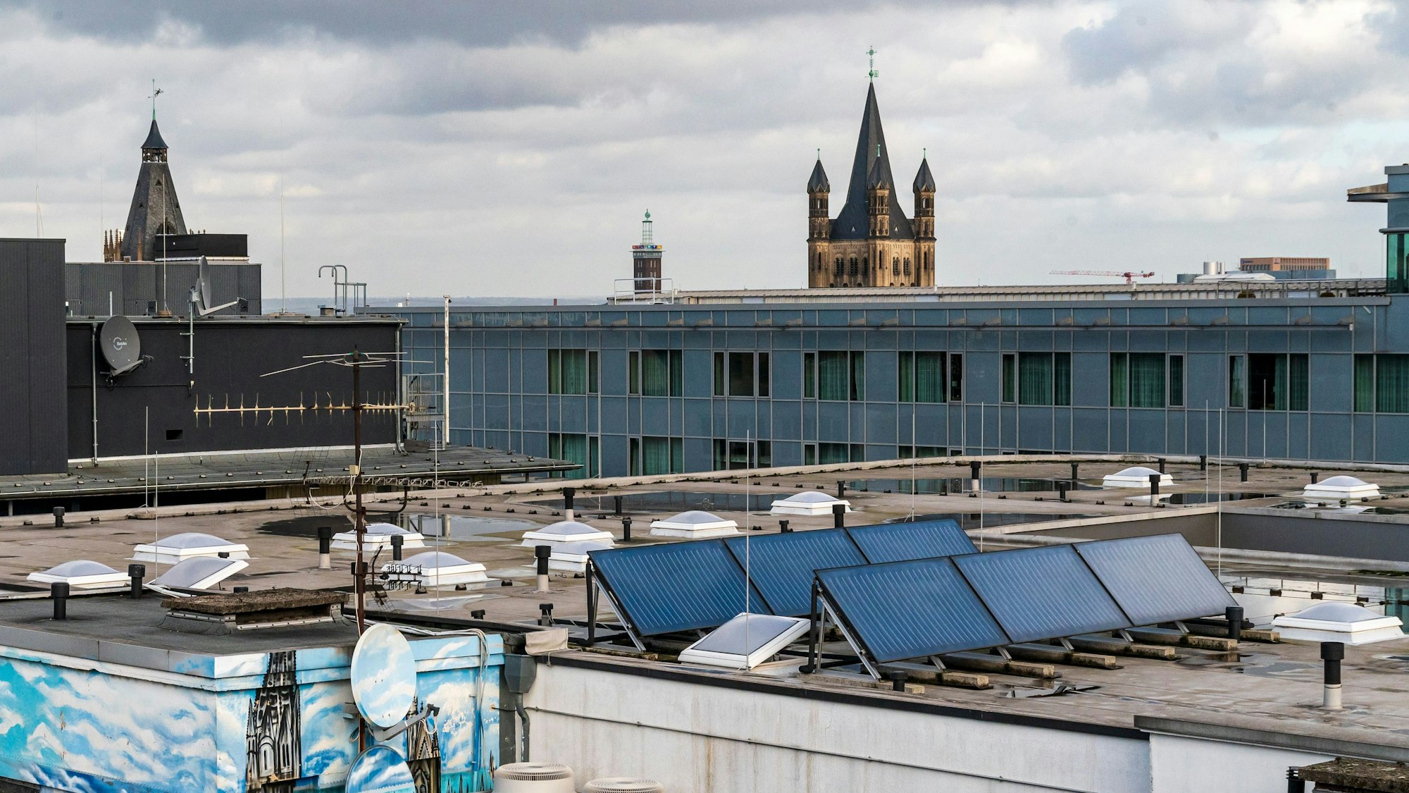 Solarzellen auf Gebäuden in der Kölner Innenstadt.
Hier: Ein Hotel- und Geschäftshaus an der Hohe Straße, Ecke Pipinstraße.
Im Hintergrund ist Groß St. Martin, und unten links, ein Graffiti was den Kölner Dom zeigt zu sehen.