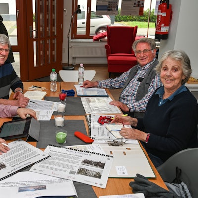 Drei Männer und eine Frau sitzen um einen Tisch.