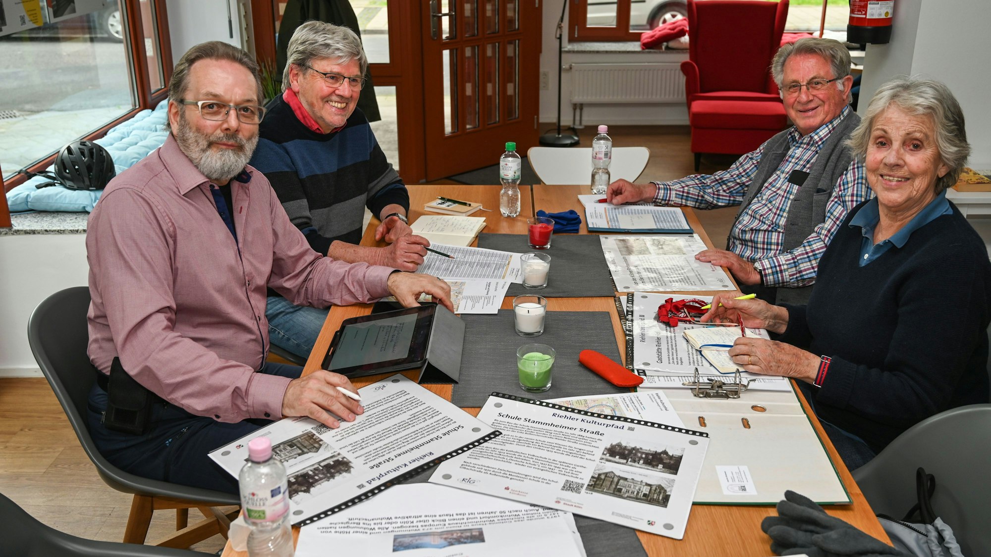Drei Männer und eine Frau sitzen um einen Tisch.