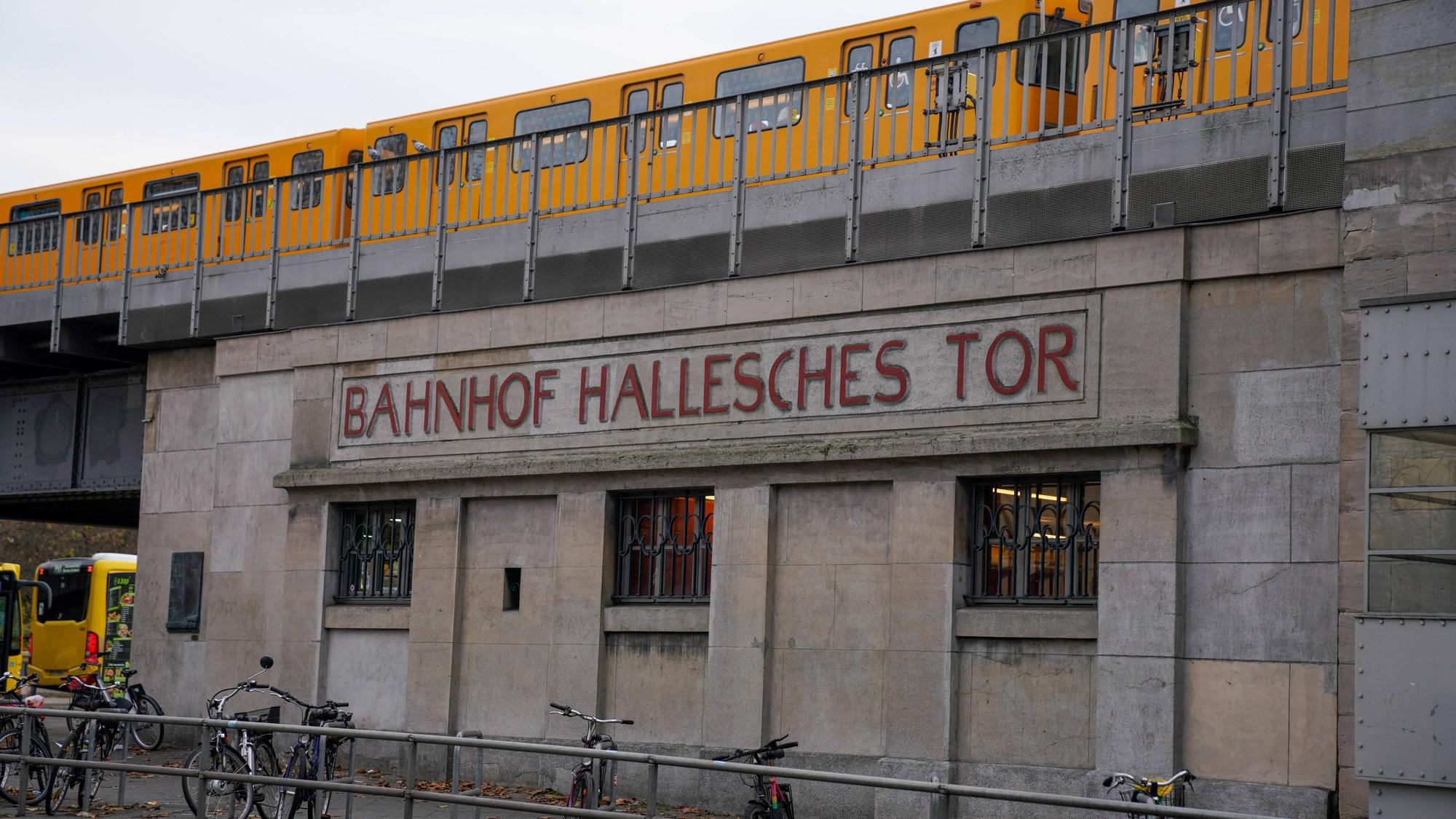 Schriftzug Hallesches Tor, Haltestelle der BVG, ein Zug der U-BAhn fährt darüber Berlin.