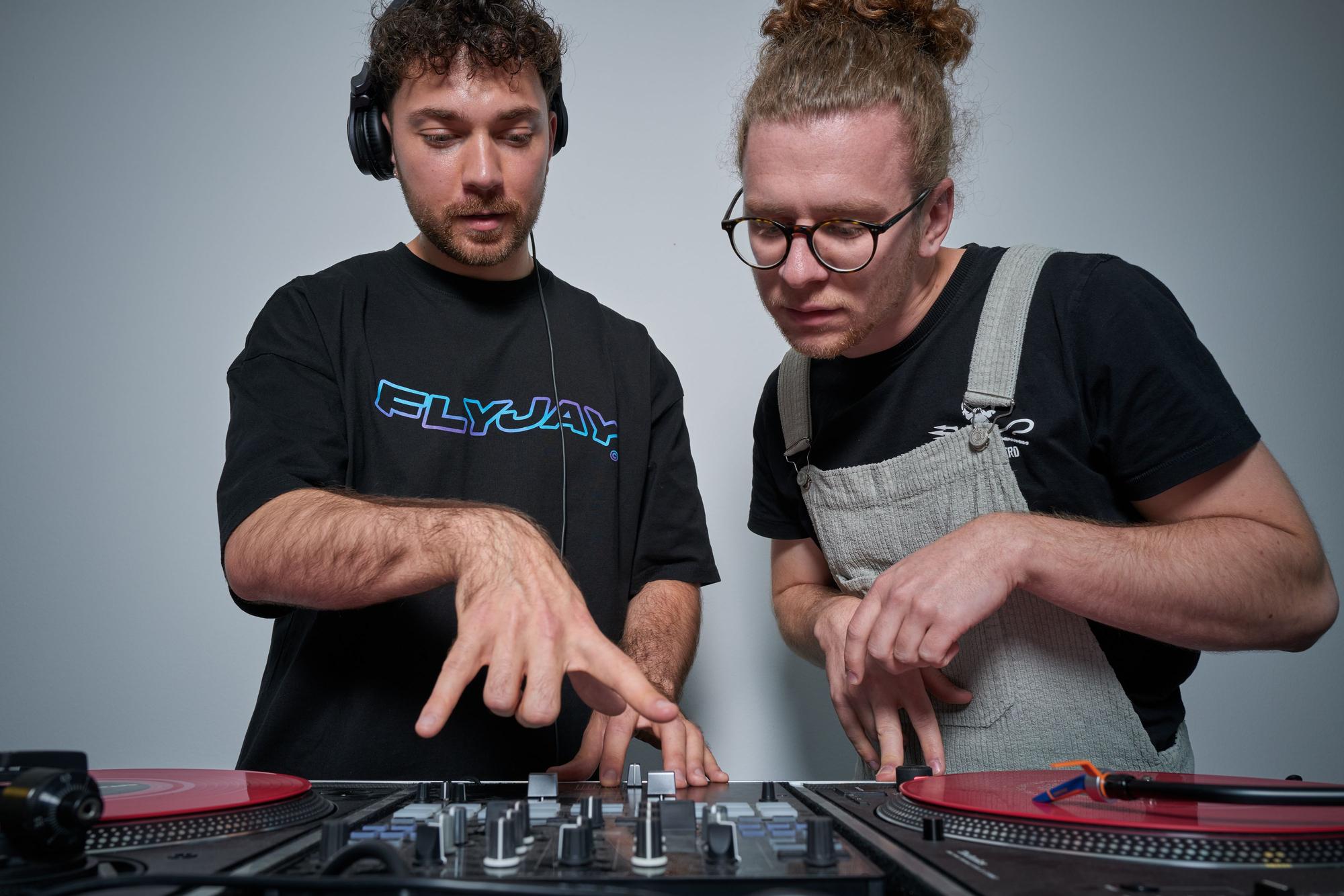 DJ Jason Carter und Student Nils Wiedemeyer schauen auf das DJ-Mischpult