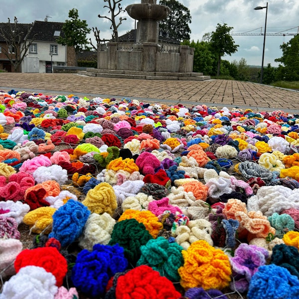 Es ist ein Teil des Kunstprojektes „Rosen für den Frieden“ zu sehen. Selbstgehäkelte Rosen wurden auf dem Boden platziert.