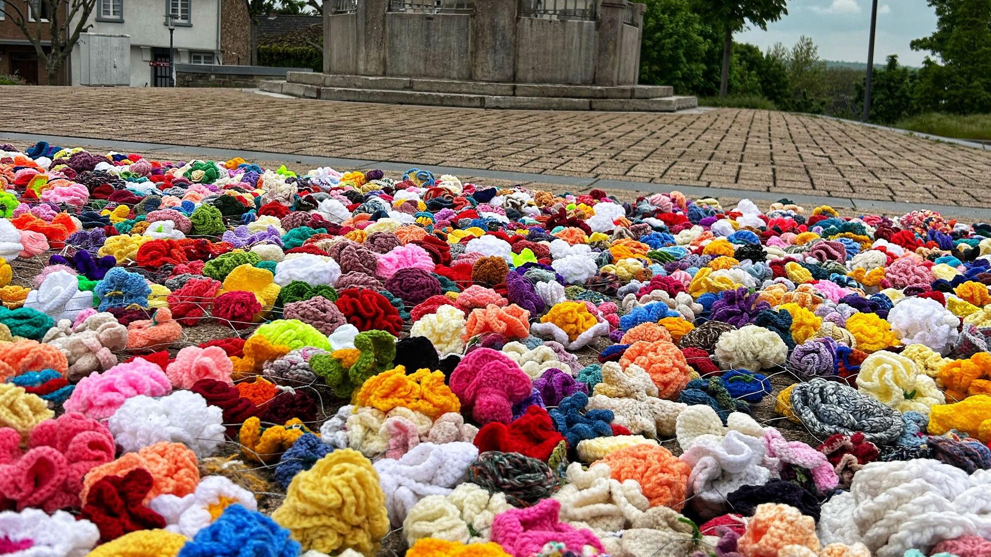 Es ist ein Teil des Kunstprojektes „Rosen für den Frieden“ zu sehen. Selbstgehäkelte Rosen wurden auf dem Boden platziert.