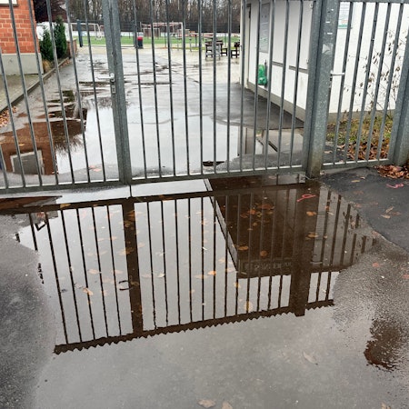 Große Pfützen auf den Wegen des Sportplatzes