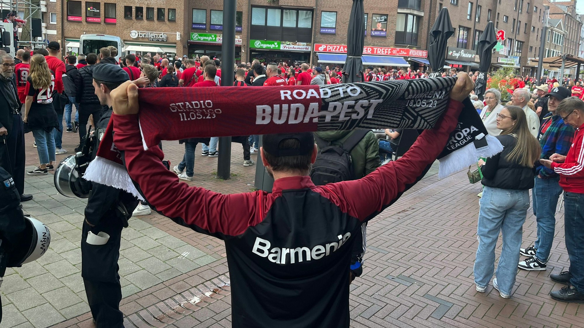 Road To Budapest steht auf dem Schal, den Bülent in der Opladener Fußgängerzone in die Höhe streckt.