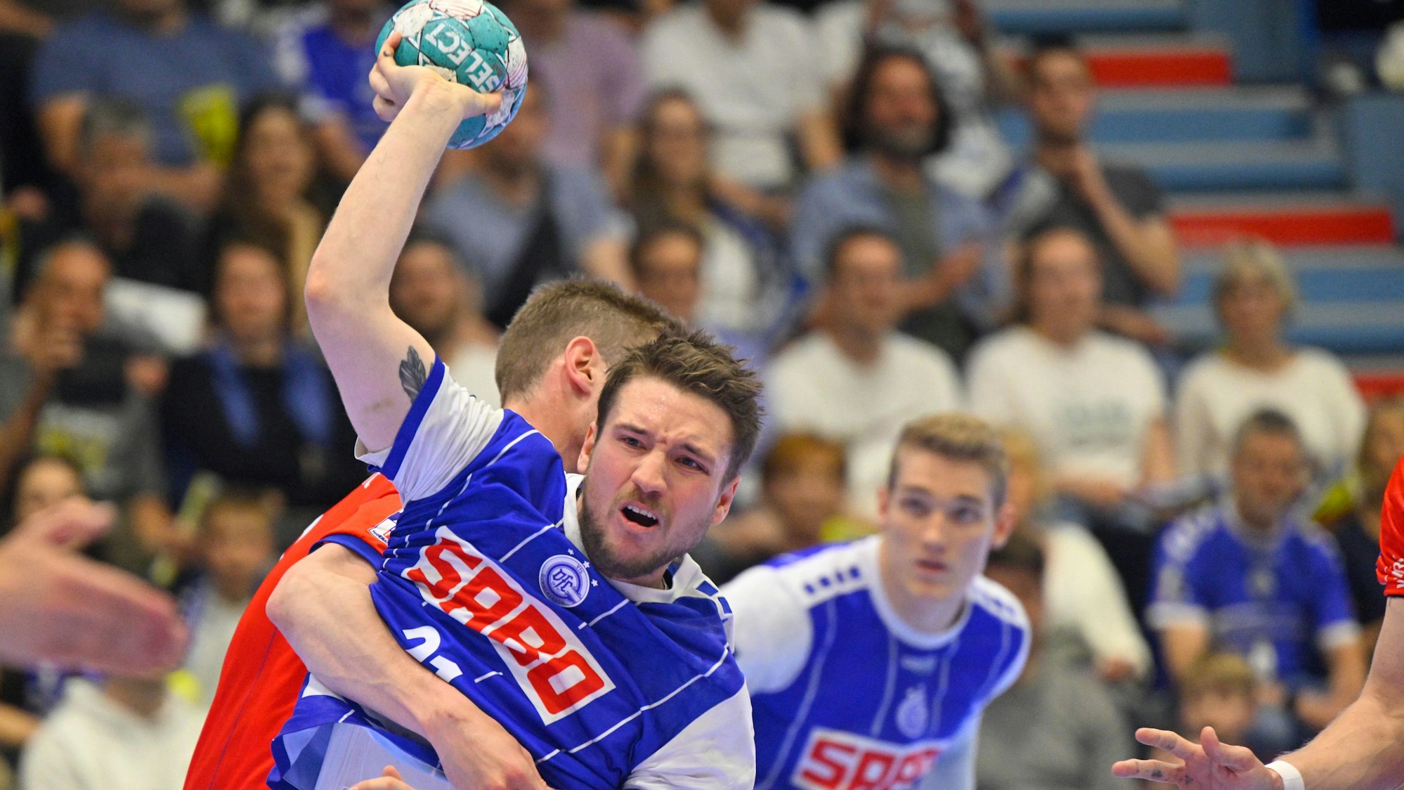 VfL-Handballer Dominik Mappes hat sich gegen seinen Gegenspieler durchgesetzt, hat den rechten Arm erhoben und setzt zum Wurf an.