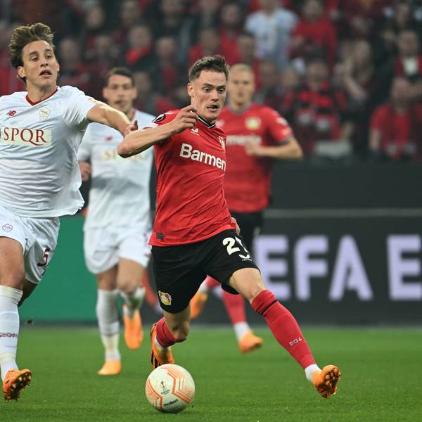 Roms Edoardo Bove in einem weißen Trikot (l) und Leverkusens Florian Wirtz in rot kämpfen um den Ball.