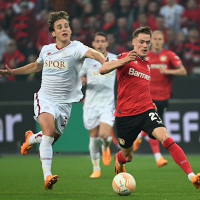 Roms Edoardo Bove in einem weißen Trikot (l) und Leverkusens Florian Wirtz in rot kämpfen um den Ball.