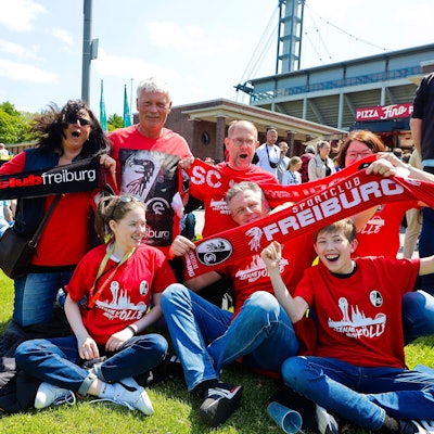 Fans vom SC Freiburg feiern vor dem DFB-Pokalfinale der Frauen und halten Schals in die Luft.