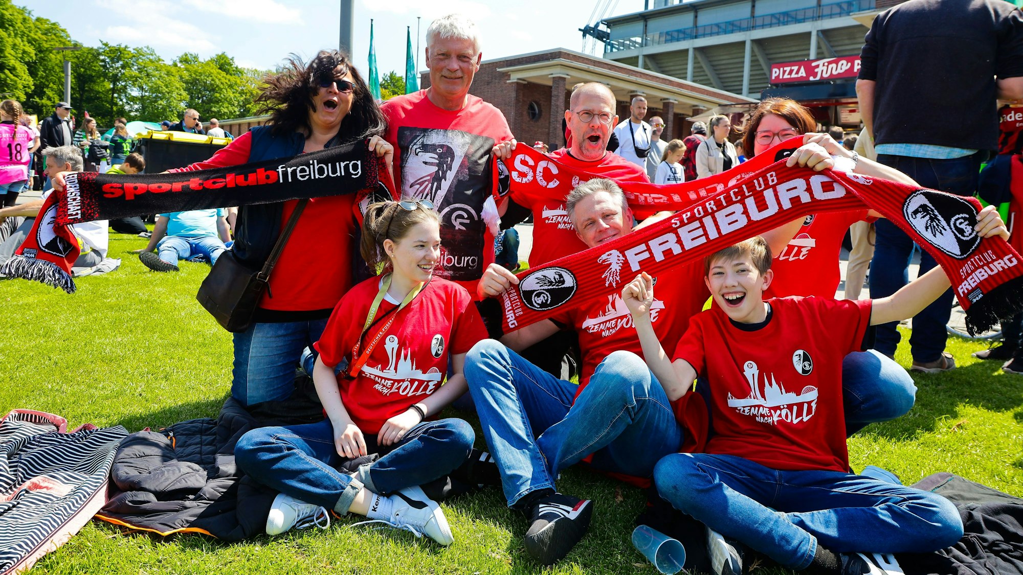 Fans vom SC Freiburg feiern vor dem DFB-Pokalfinale der Frauen und halten Schals in die Luft.