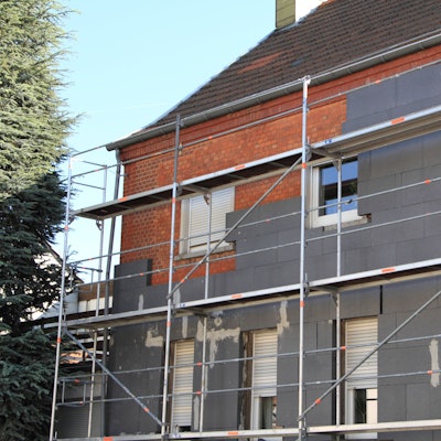 Eine Hausfassade wird von außen neu gedämmt.