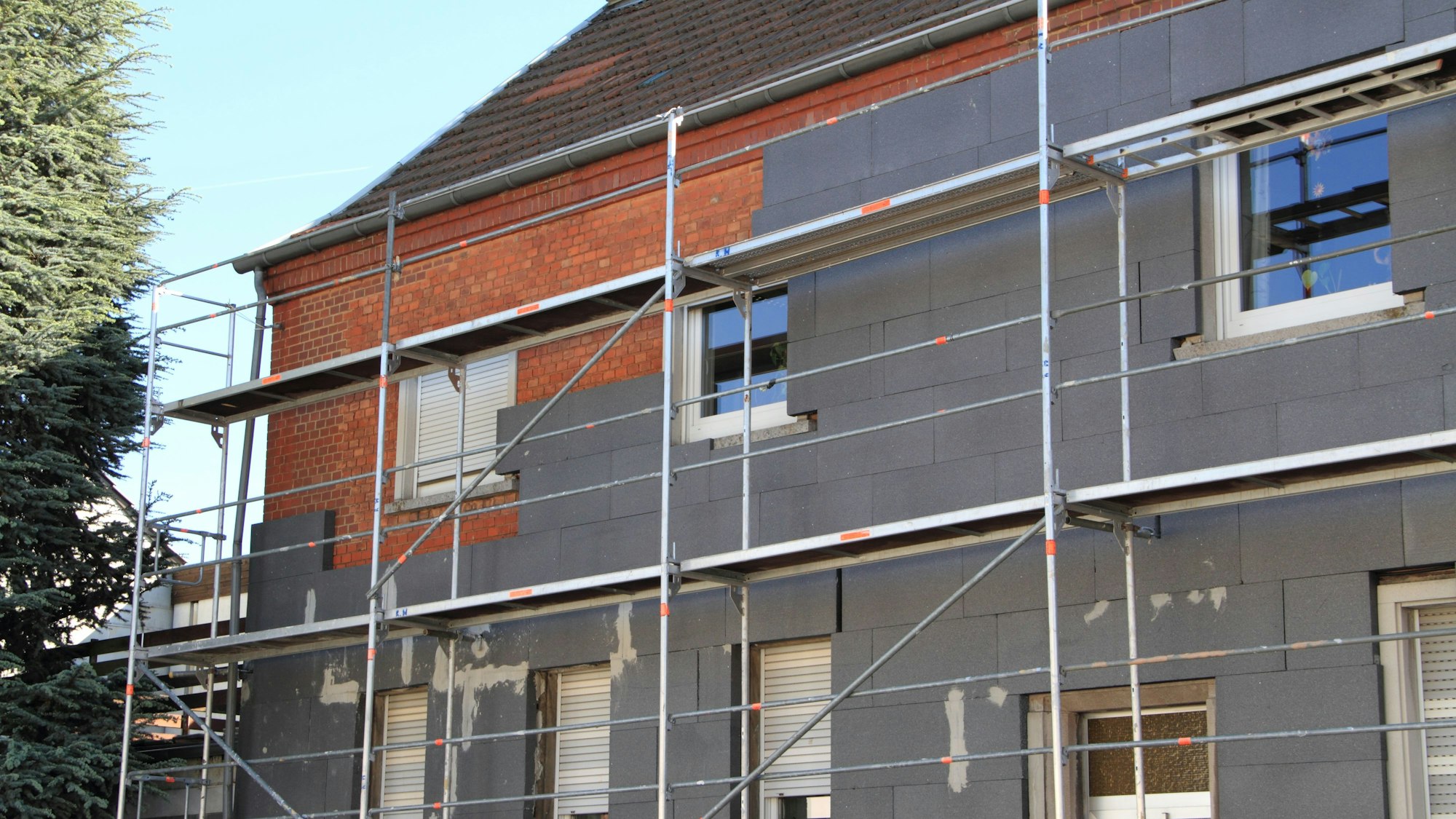 Eine Hausfassade wird von außen neu gedämmt.