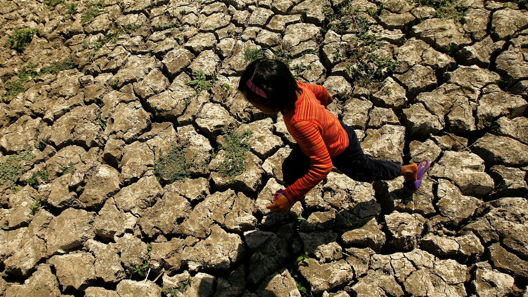 Ein Kind läuft über einen ausgetrockneten Boden auf den Phillipinen.
