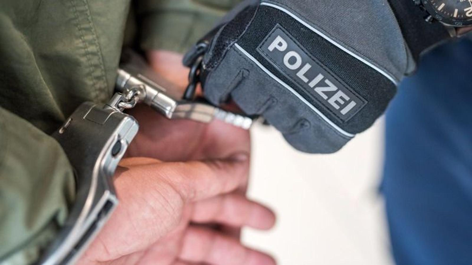 Die Polizei nimmt jemanden mit Handschellen fest.