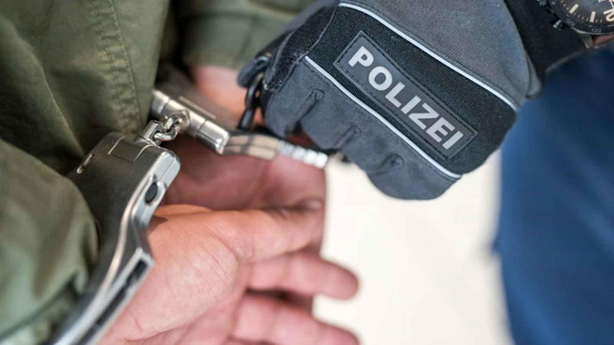 Die Polizei nimmt jemanden mit Handschellen fest.