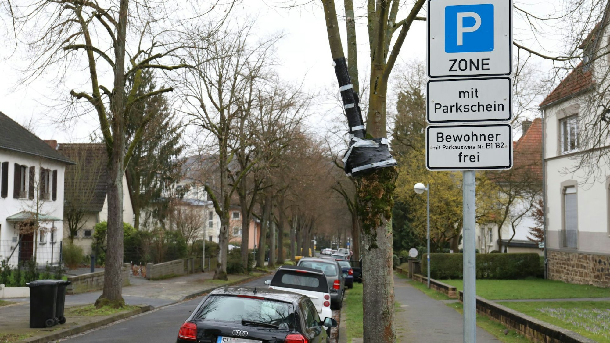 Ein Straßenschild weist die Giradetallee in der Bad Honnefer City als parkgebührenpflichtig aus. Am rechten Fahrbahnrand parken Autos.