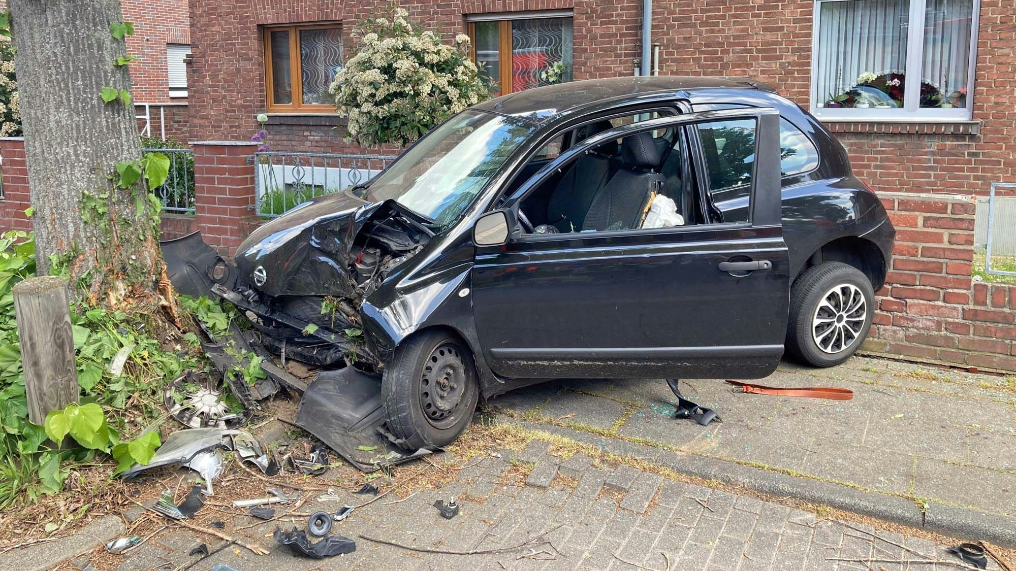 Der Pkw wurde zwischen einem Baum und einem Haus eingeklemmt.