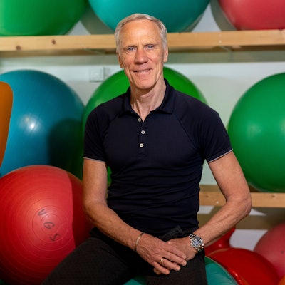 Ingo Froböse guckt in die Kamera, um ihn herum liegen Medizinbälle.