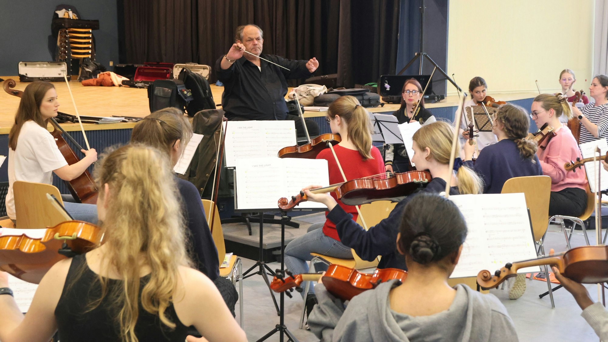 Ein Dirigent leitet ein junges Orchester an.