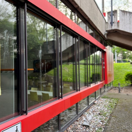An einer Glasscheibe der Mensa hängt ein Plakat, auf dem darüber informiert wird, dass das Gelände nach Betriebsschluss nicht mehr betreten werden darf.