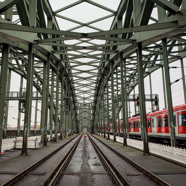 Die Gleise der Kölner Hohenzollernbrücke. Im Hintergrund ist der Kölner Dom zu sehen, rechts fährt eine S-Bahn vorbei. (Symbolbild)