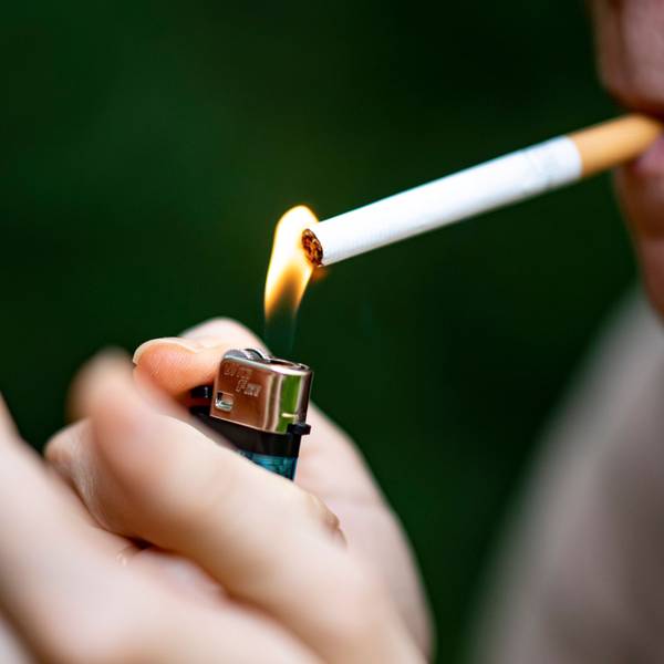 Eine Frau zündet sich mit einem Feuerzeug eine Zigarette an.