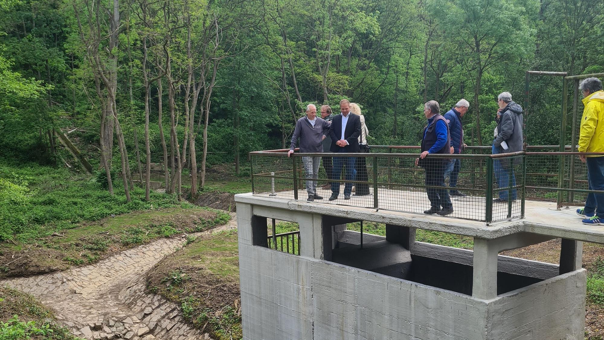 Das Auslaufbauwerk am Hochwasserrückhaltebecken wird von mehreren Menschen inspiziert.