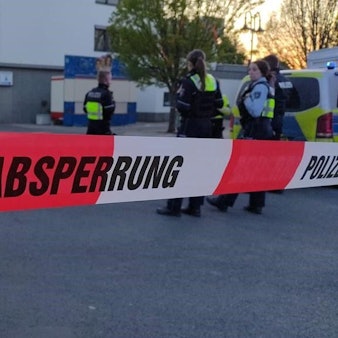 Rot-weißes Absperrband der Polizei sperrt den Bereich vor der Volksbank in Mechernich ab, im Hintergrund sieht man Polizistinnen und Kirmesbuden.