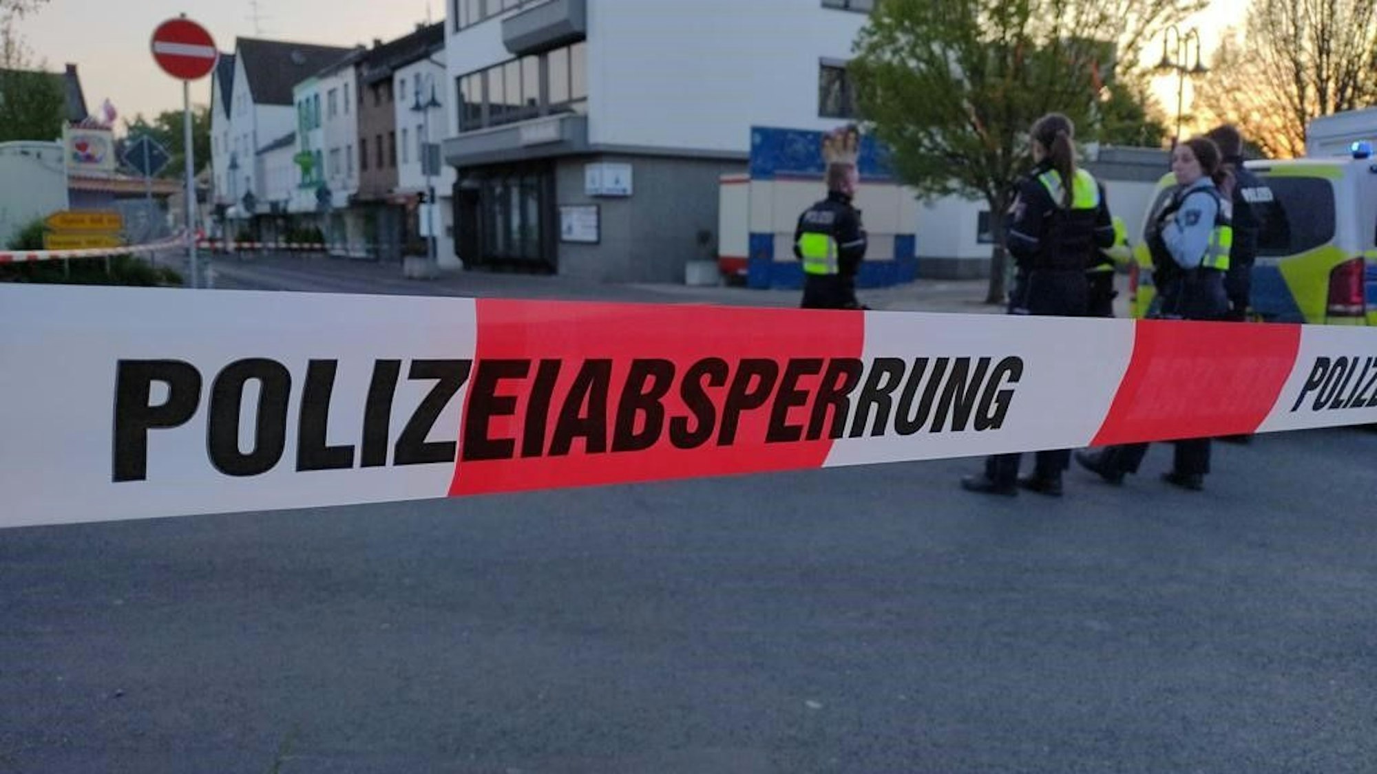 Rot-weißes Absperrband der Polizei sperrt den Bereich vor der Volksbank in Mechernich ab, im Hintergrund sieht man Polizistinnen und Kirmesbuden.