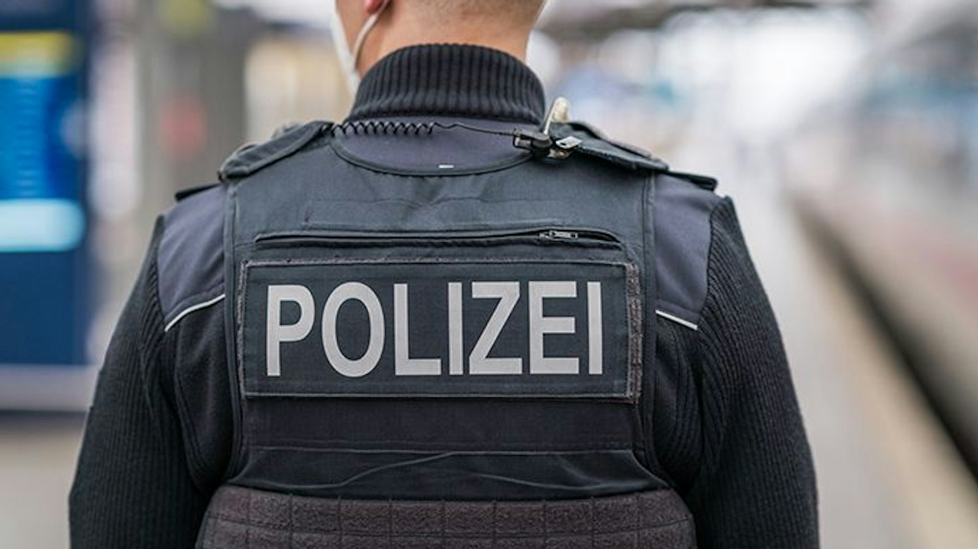 Auf der Weste eines Polizisten steht der Polizei-Schriftzug (Symbolbild)
