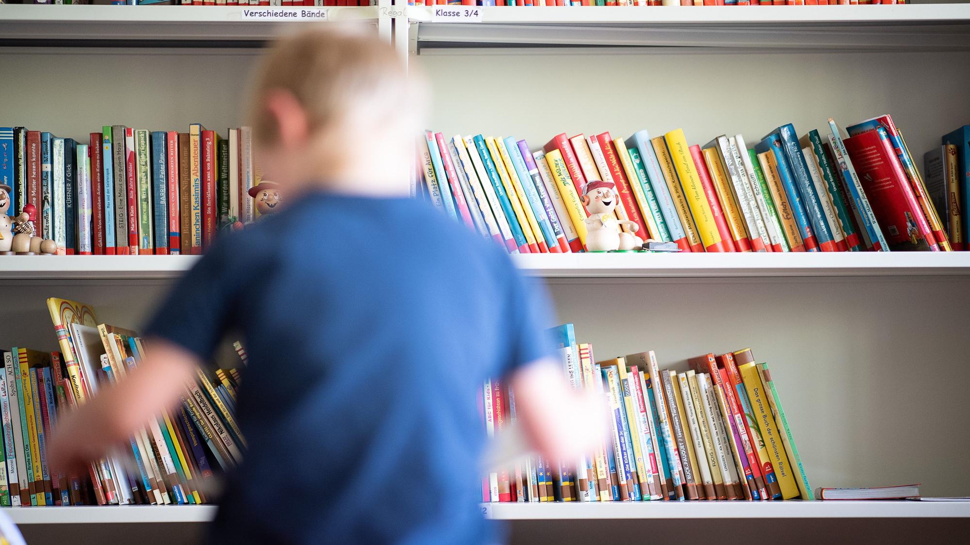 Ein Junge von hinten vor einem Bücher-Regal