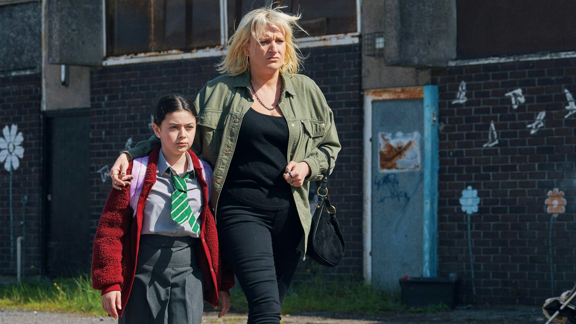 Mutter und Tochter gehen eine Straße entlang.