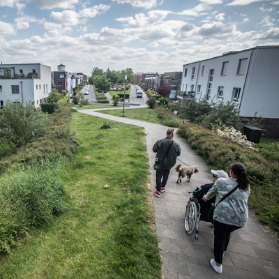 Die weißen Häuser links und rechts des Fußwegs gehören zur Nutzergenossenschaft Neue Bahnstadt Opladen (NgNBsO) an der Adam-Riese-Straße.