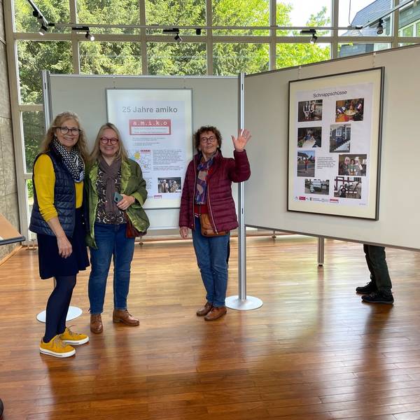 Drei Frauen stehen vor einer Ausstellungstafel.