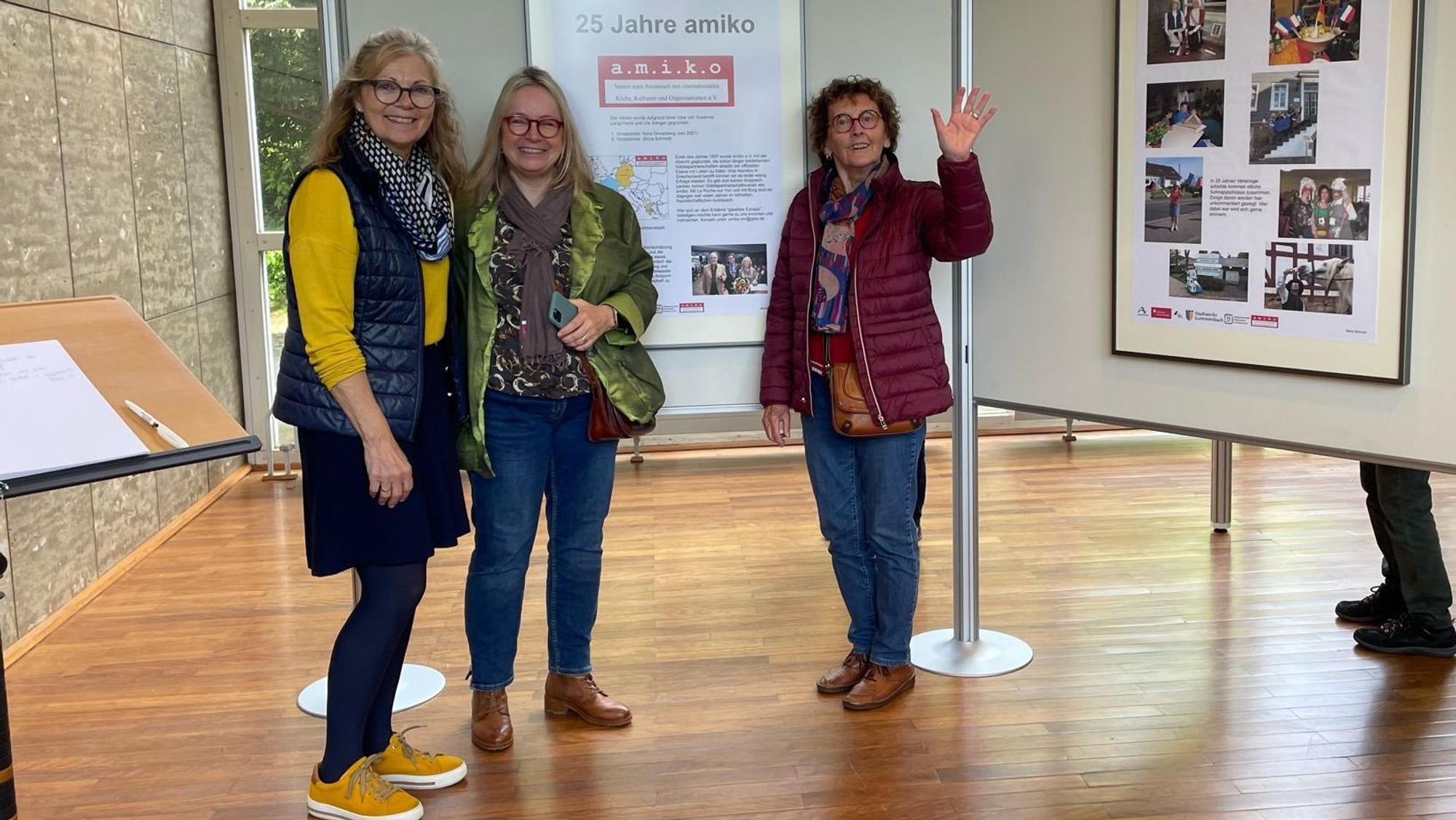 Drei Frauen stehen vor einer Ausstellungstafel.