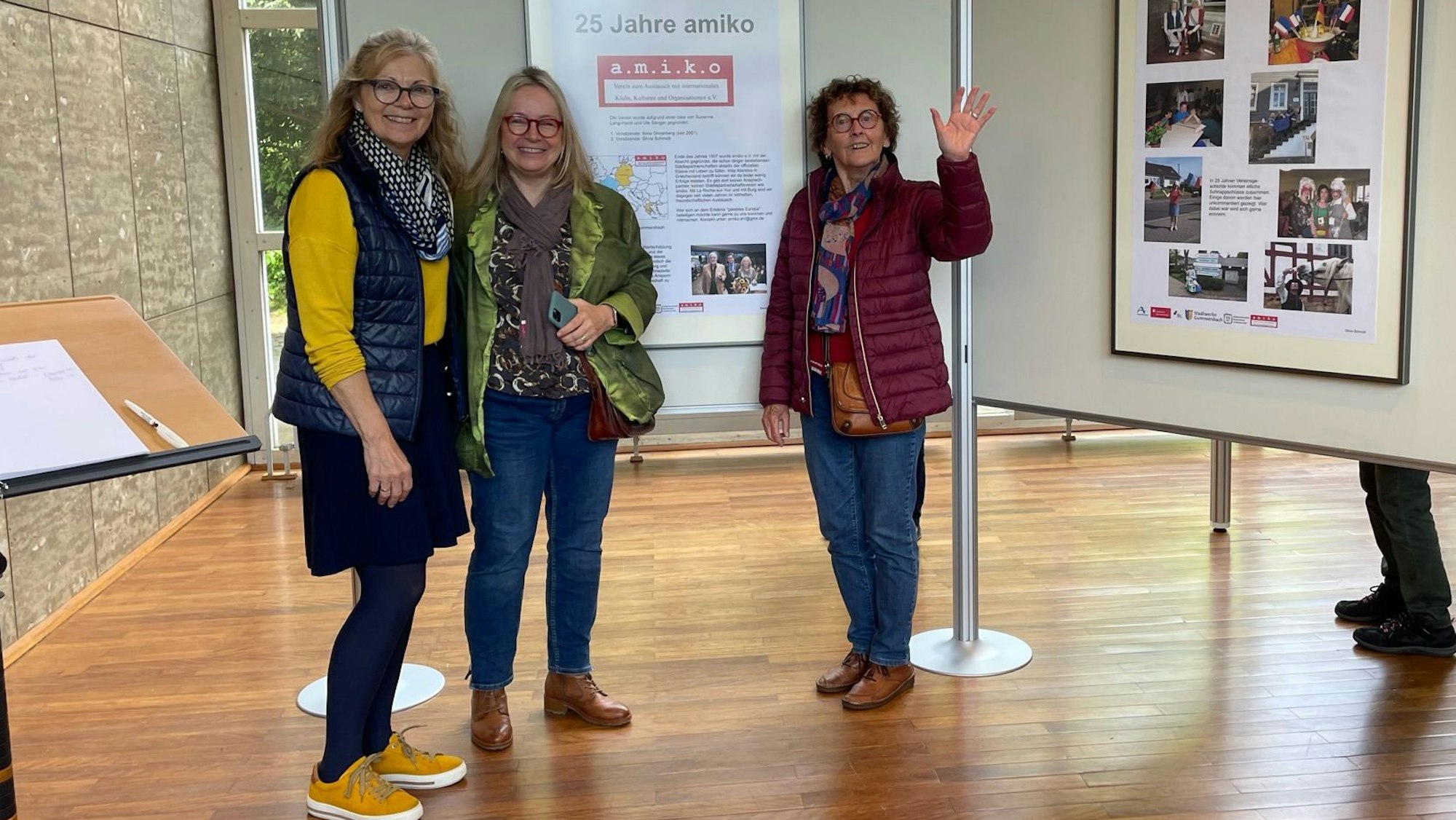 Drei Frauen stehen vor einer Ausstellungstafel.