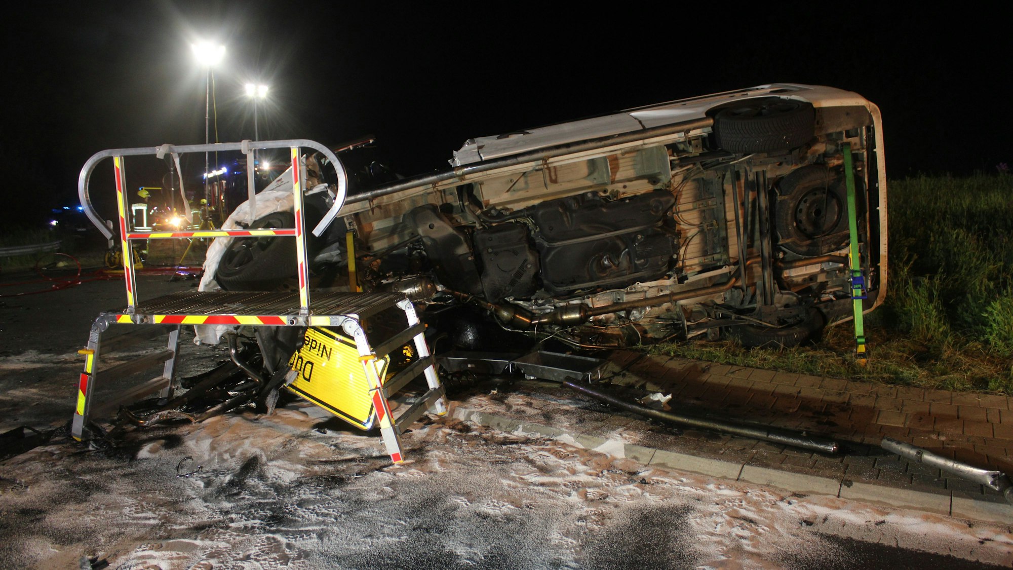 Das Fahrzeug liegt auf der Seite, man erkennt Schäden. Davor steht ein Podest. Sand ist ausgestreut.