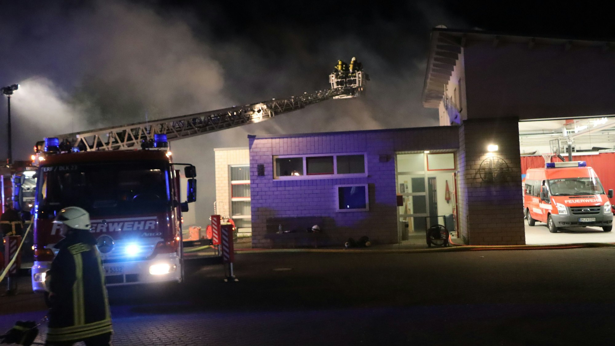 Auf dem Kran eines Feuerwehrautos befinden sich zwei Feuerwehrmänner im Einsatz.